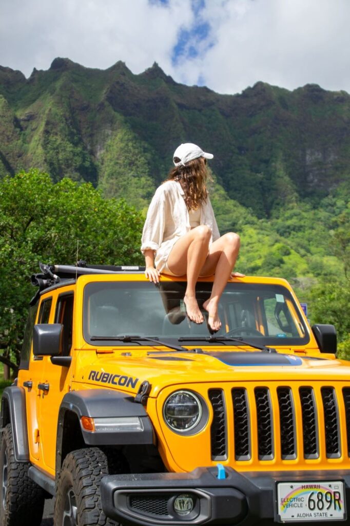 Valentina sitting on a yellow jeep surrounded by mountains