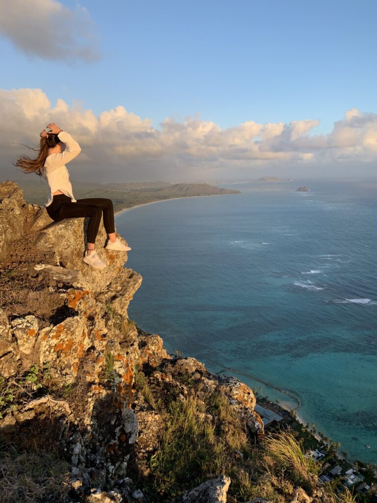 valentina sitting on thr edge of a cliff overlooking the sea